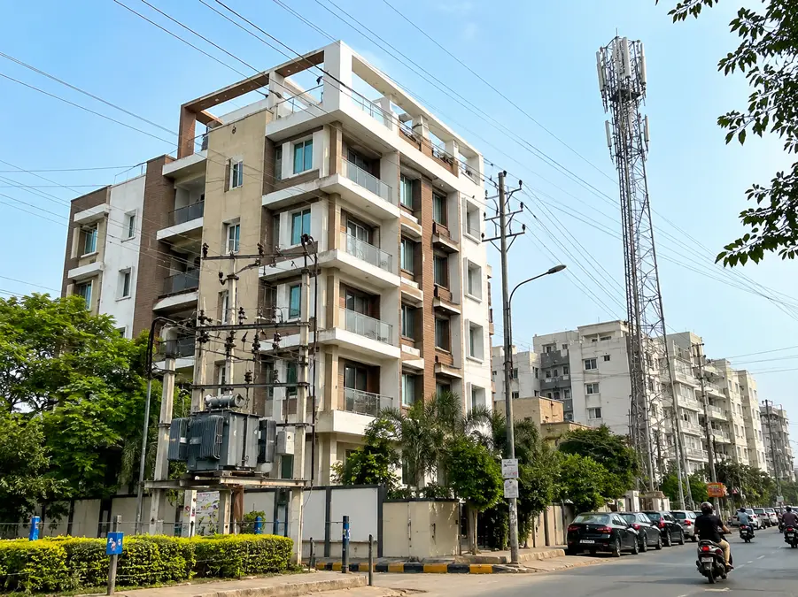Stage B — apartment building beside a transformer, power lines and a telecom tower